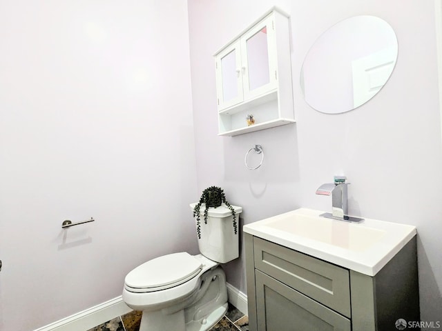 half bath featuring vanity, toilet, and baseboards