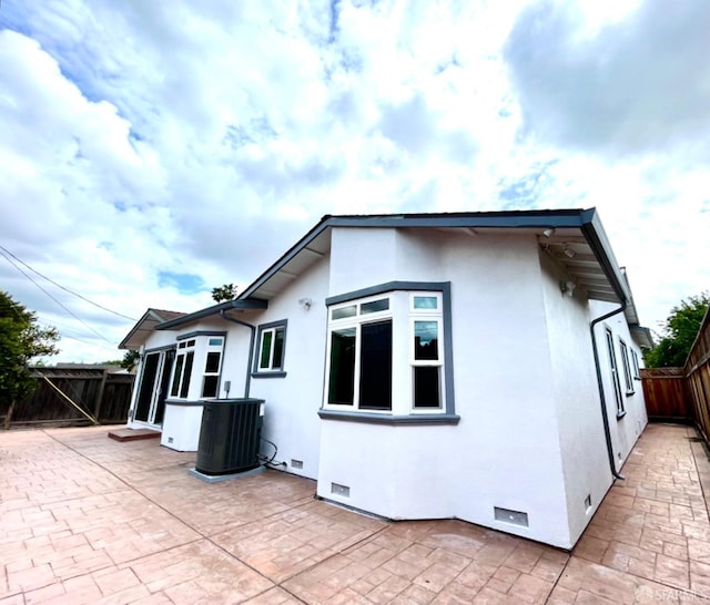 rear view of house featuring cooling unit, a patio, crawl space, stucco siding, and a fenced backyard