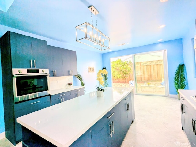 kitchen with stainless steel oven, hanging light fixtures, a notable chandelier, backsplash, and a kitchen island