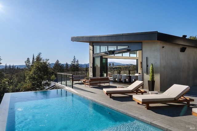 view of pool featuring an infinity pool, a mountain view, a bar, and a patio