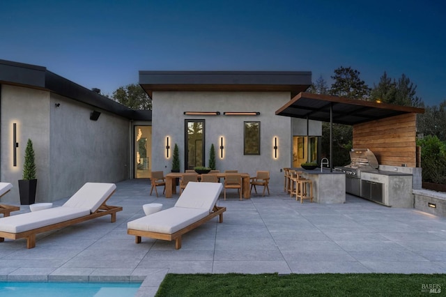 back of property featuring a patio, stucco siding, a sink, exterior kitchen, and outdoor wet bar