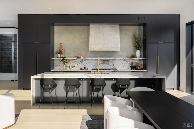 kitchen featuring decorative backsplash, light wood-type flooring, a kitchen bar, and modern cabinets