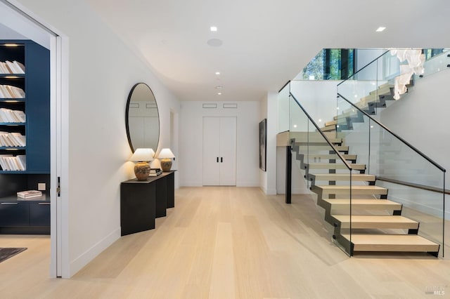 foyer with light wood-type flooring, stairs, and baseboards