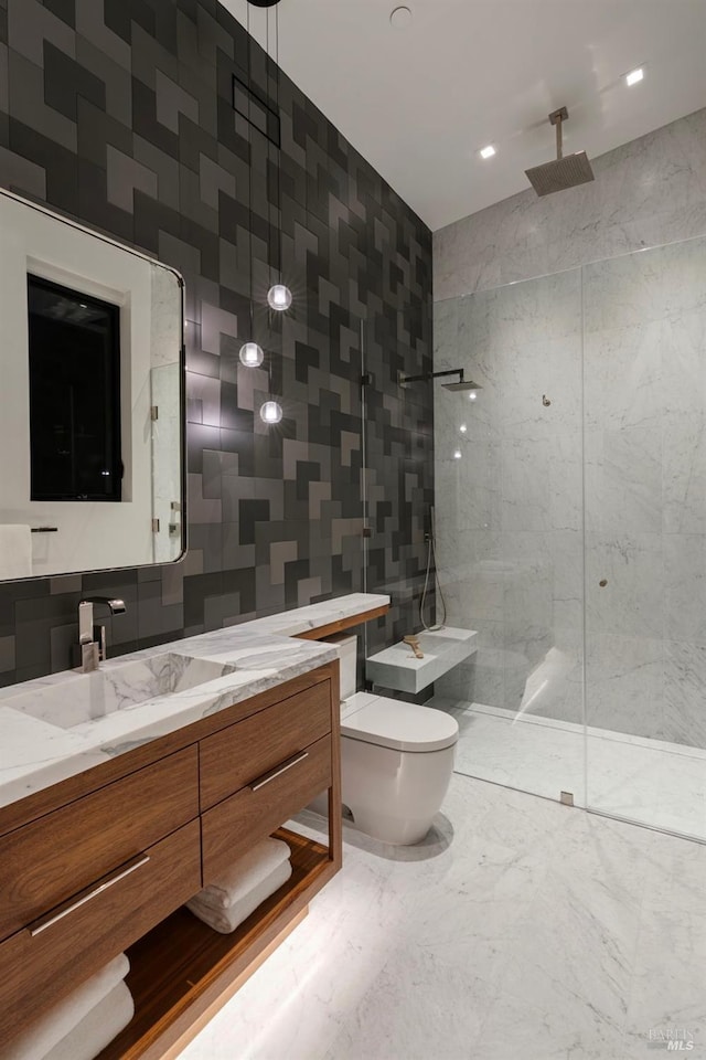bathroom featuring marble finish floor, tile walls, toilet, vanity, and a walk in shower