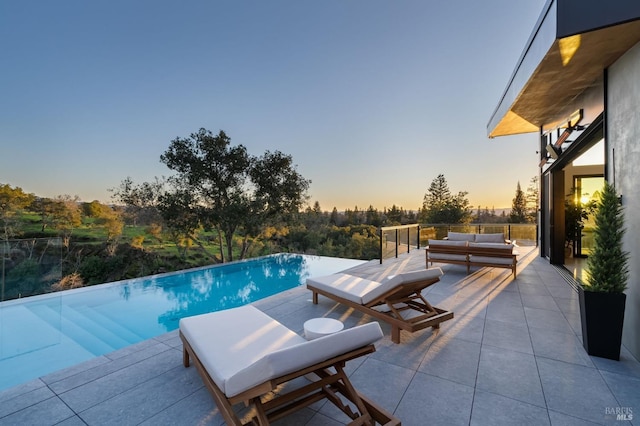view of pool with an infinity pool, a patio, and an outdoor living space