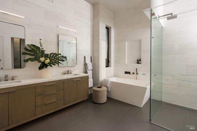 full bathroom featuring a freestanding tub, a sink, tile walls, and tile patterned floors