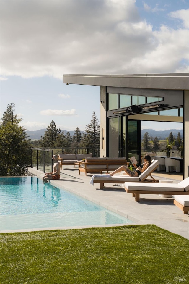 view of swimming pool with an infinity pool, a patio, and a mountain view