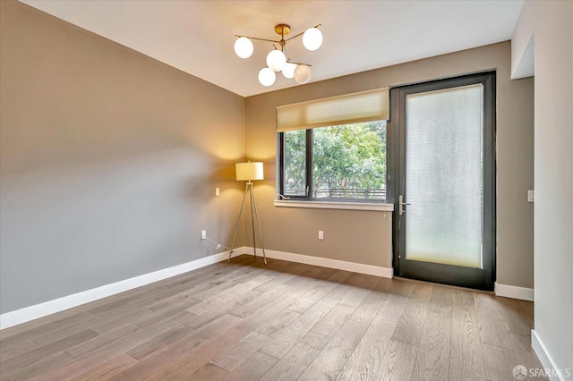 spare room with wood-type flooring and a chandelier