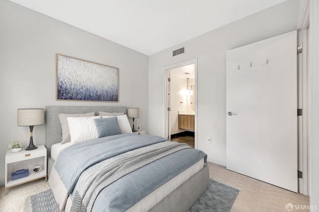 bedroom with light wood-type flooring and ensuite bathroom