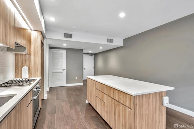 kitchen with appliances with stainless steel finishes, dark hardwood / wood-style floors, and a kitchen island