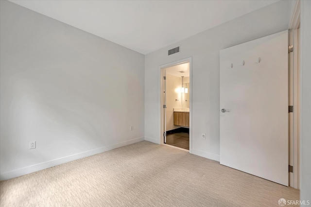 unfurnished bedroom with ensuite bath and light colored carpet