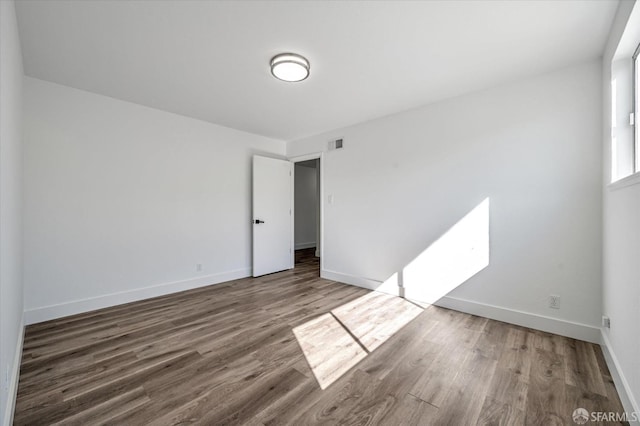 spare room with visible vents, baseboards, and wood finished floors