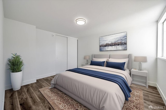 bedroom featuring a closet, baseboards, and dark wood-style flooring