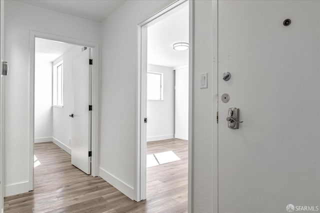 hall with light wood-type flooring and baseboards