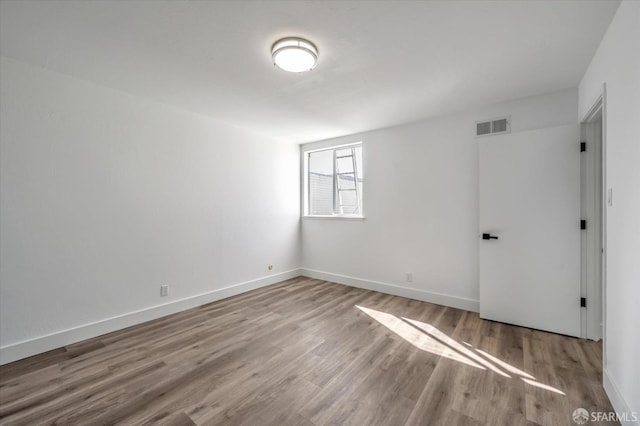 empty room featuring light wood finished floors, visible vents, and baseboards