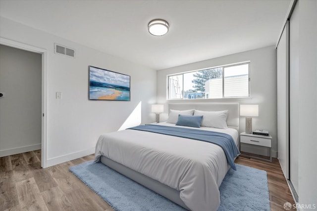 bedroom featuring light wood-style flooring, visible vents, and baseboards