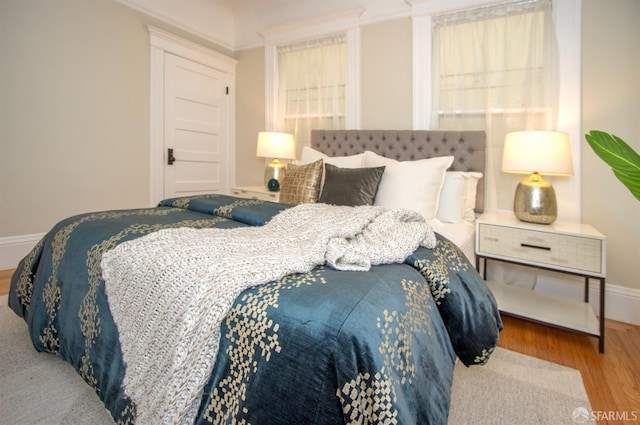 bedroom with wood finished floors, baseboards, and ornamental molding