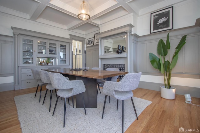 dining room with wood finished floors, beamed ceiling, coffered ceiling, and a decorative wall