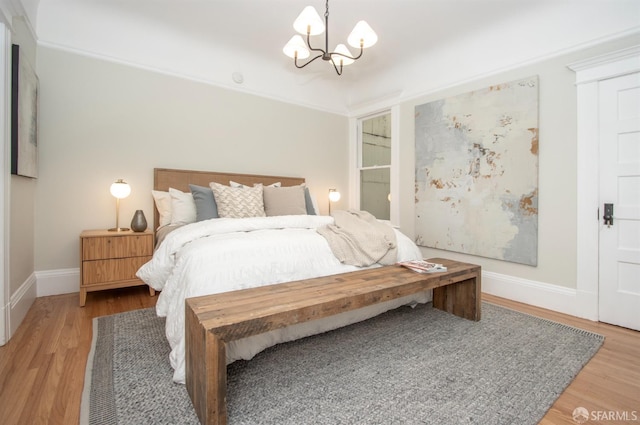 bedroom featuring a chandelier, wood finished floors, and baseboards