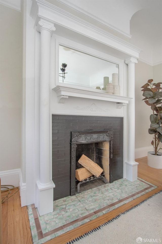 detailed view of a tile fireplace, baseboards, wood finished floors, and ornamental molding