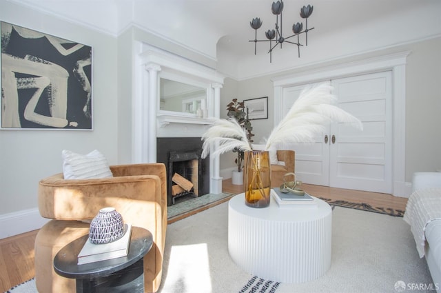 living area featuring wood finished floors, a chandelier, a fireplace, and baseboards