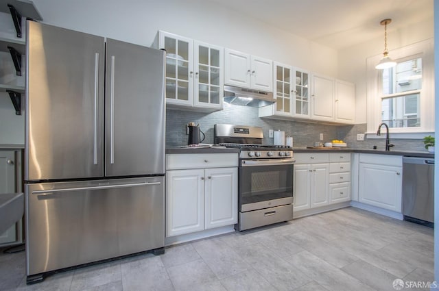 kitchen featuring stainless steel appliances, under cabinet range hood, dark countertops, and decorative backsplash