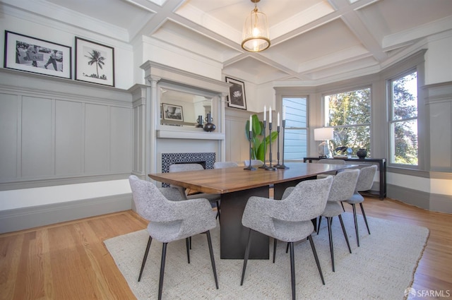 dining space with a fireplace, a decorative wall, coffered ceiling, light wood-style flooring, and beam ceiling