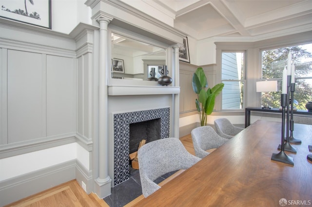 office space with a decorative wall, a fireplace, coffered ceiling, ornate columns, and beamed ceiling