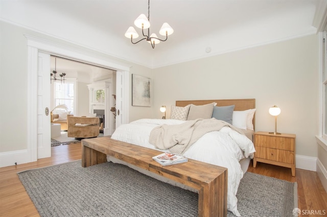 bedroom with a chandelier, wood finished floors, and baseboards