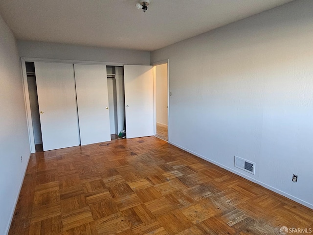 unfurnished bedroom with dark parquet flooring and a closet