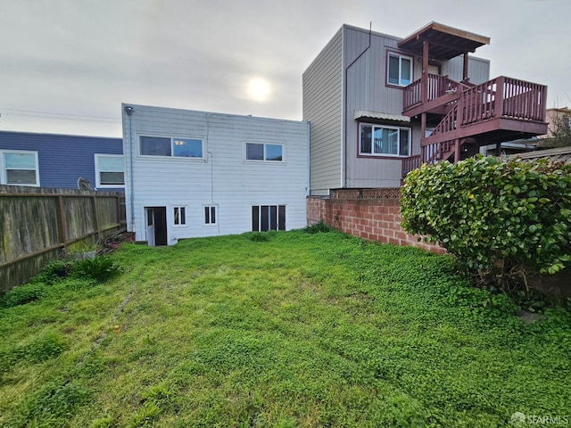 rear view of house featuring a lawn and a wooden deck