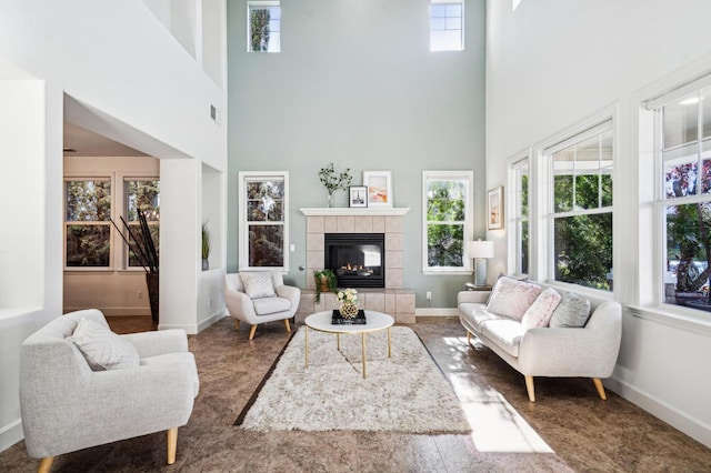 living room with a towering ceiling and a tiled fireplace