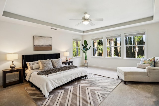 bedroom with carpet floors, ceiling fan, and a raised ceiling