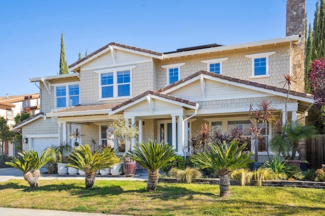 view of front of home featuring a porch, a garage, and a front yard