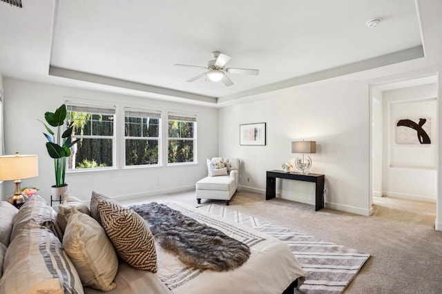 carpeted bedroom featuring ceiling fan and a raised ceiling