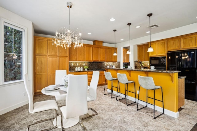 kitchen featuring black appliances, a kitchen bar, tasteful backsplash, dark stone countertops, and an island with sink