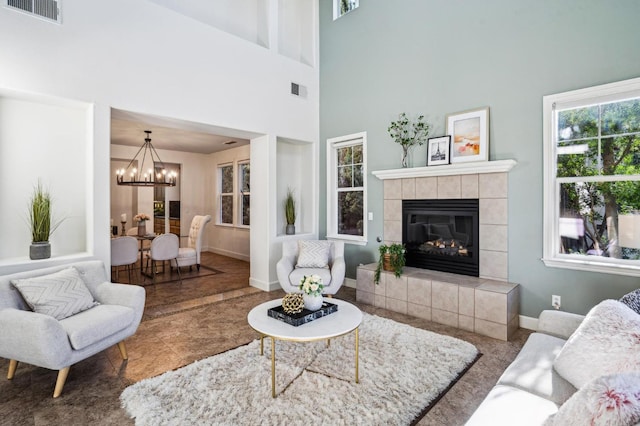 living room featuring a chandelier, a towering ceiling, and a fireplace