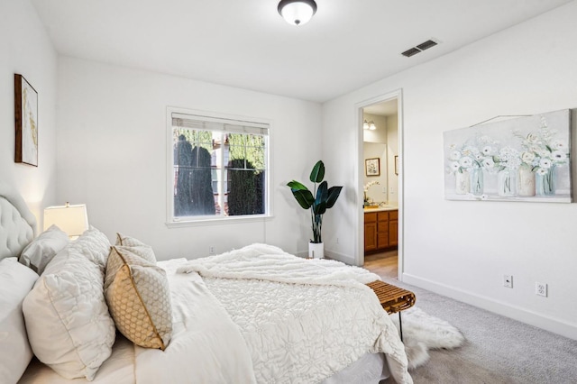 bedroom featuring light carpet and ensuite bath