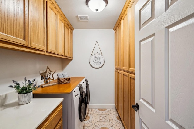 clothes washing area with cabinets and washing machine and clothes dryer