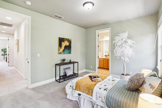 bedroom with connected bathroom and light colored carpet