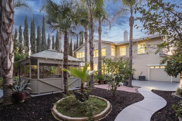 yard at dusk with a garage, a gazebo, and cooling unit