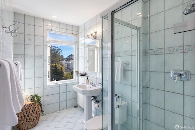 bathroom with toilet, tile patterned flooring, tile walls, and walk in shower