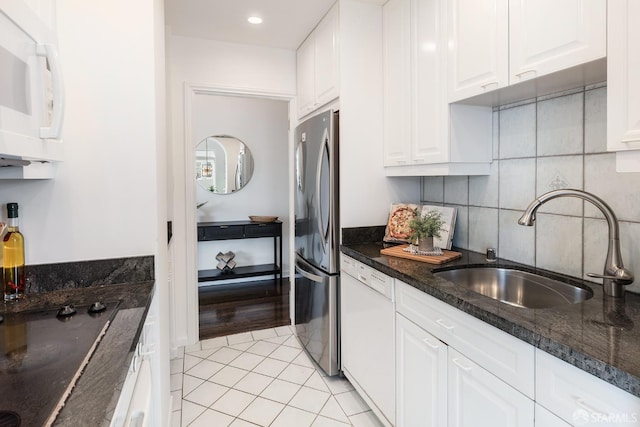 kitchen featuring dark stone counters, white appliances, sink, white cabinets, and light tile patterned flooring