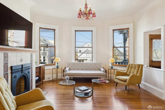 living room with an inviting chandelier, a fireplace, and wood-type flooring