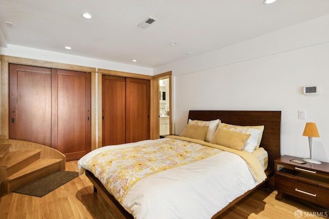 bedroom featuring multiple closets and light wood-type flooring