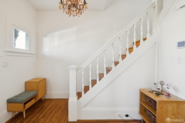 staircase with hardwood / wood-style floors and a notable chandelier