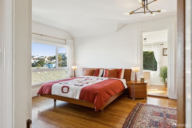 bedroom featuring vaulted ceiling, an inviting chandelier, connected bathroom, and hardwood / wood-style floors