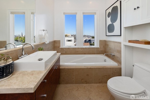 bathroom with vanity, tiled tub, and toilet