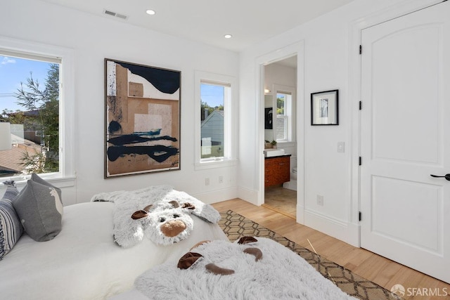 bedroom featuring light hardwood / wood-style flooring and ensuite bathroom