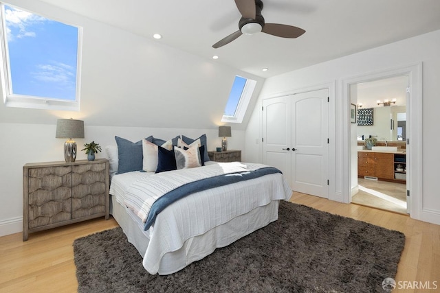 bedroom with hardwood / wood-style flooring, ceiling fan, lofted ceiling with skylight, ensuite bathroom, and a closet